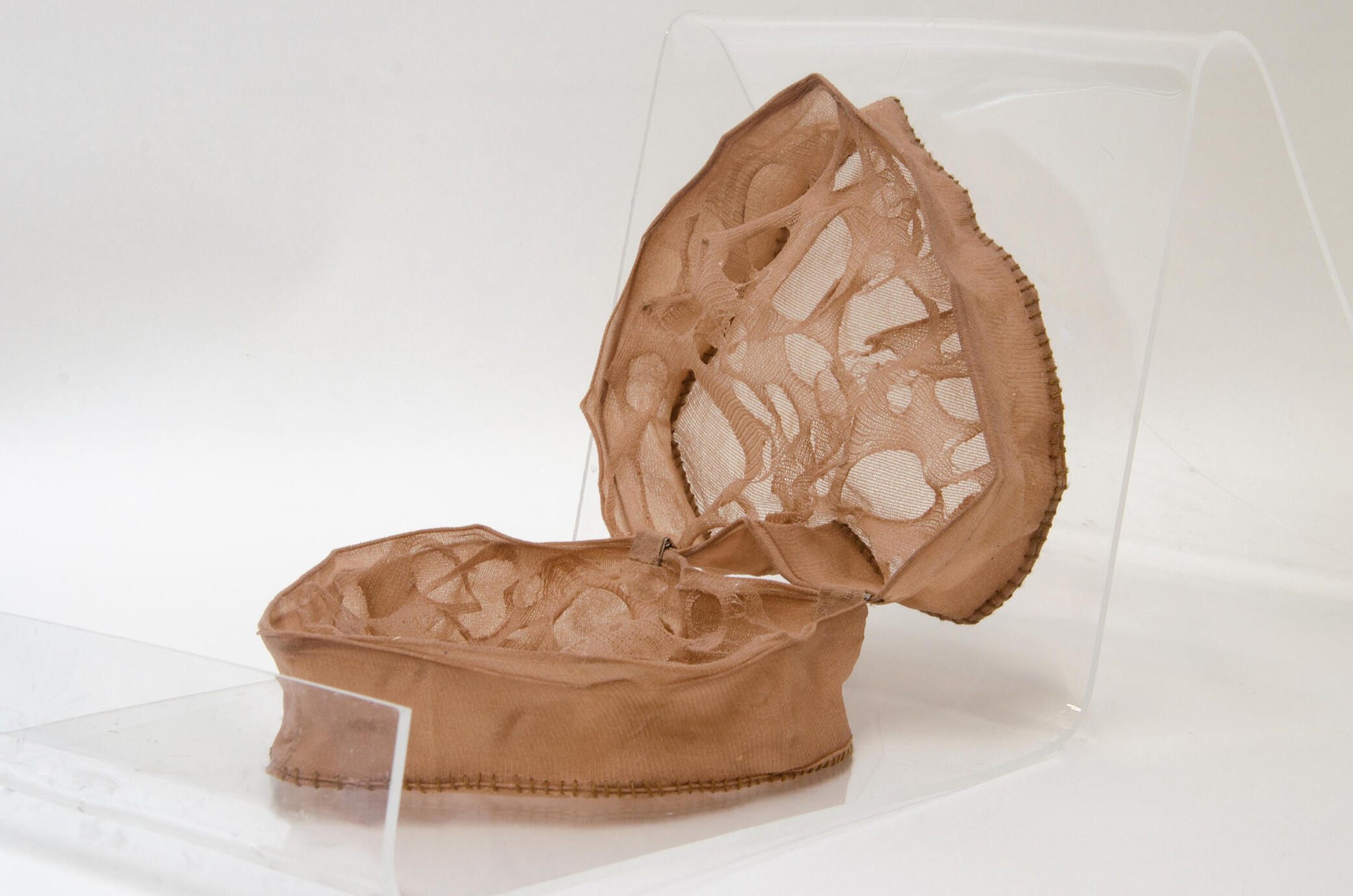 A heart shaped box made from light tan nylon tights material with repeated holes stretching across the inside of the box.